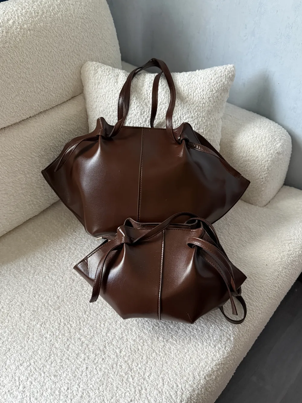 دو کیف چرم قهوه‌ای اِلودی روی مبل کرم